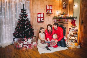family reading a book near a Christmas tree