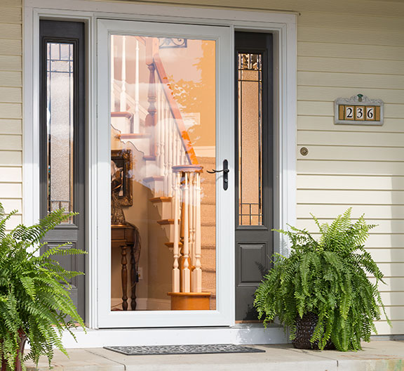Closeup of exterior front entry area showing full glass white storm door with entry door open to view inside entryway