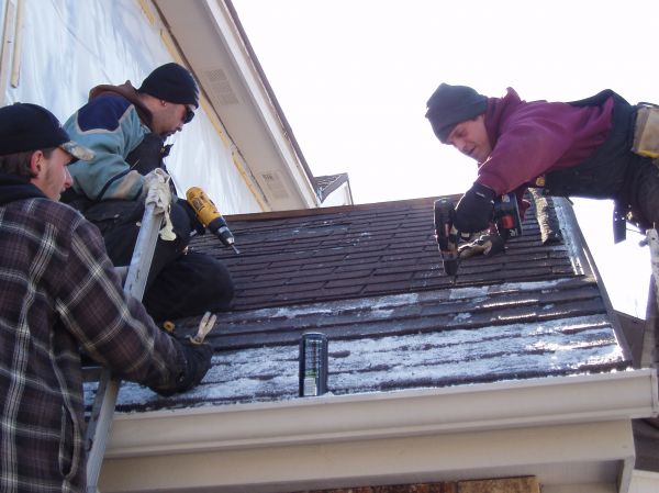 crew on roof installing roofing in the snow