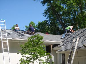 Crew on rooftop installing metal roofing and solar panel mounts