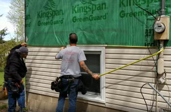 Two men installing a section of tan siding Two men installing tan siding