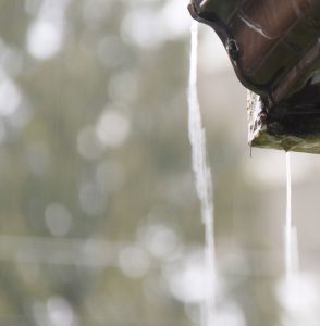 closeup of rain overflowing the corner of a gutter