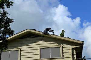 Man top of home repairing roof