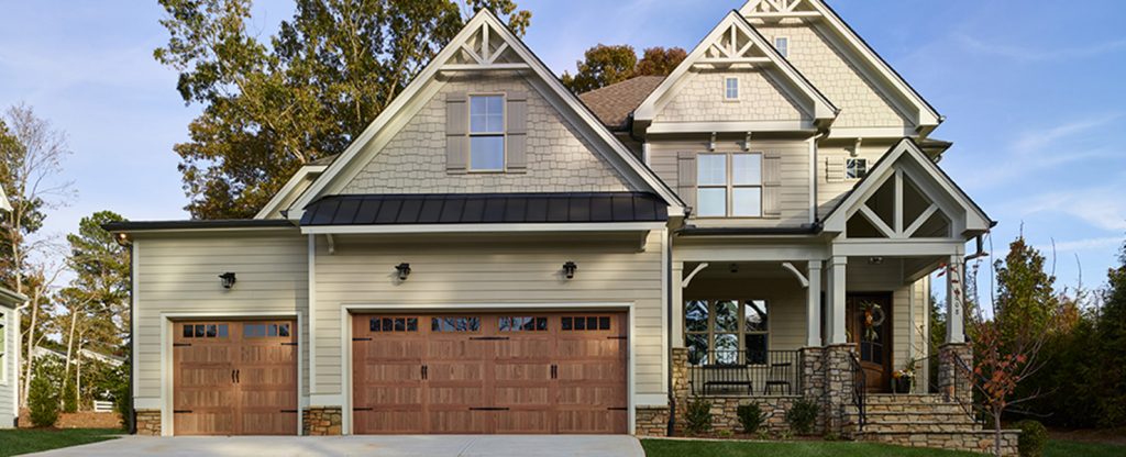 front of two-story home with tan siding, rust colored garage doors