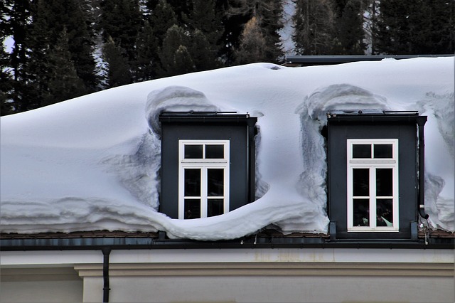 Closeup of roof with heavy snow accumulation around two dormers.