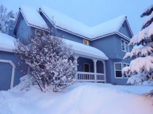 Two-story blue home covered in snow