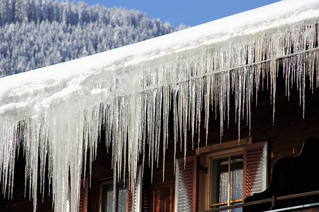 Ice dam and icicles at edge of roof on home