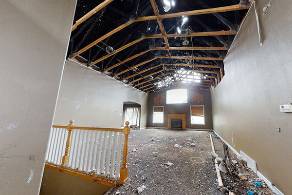 Commercial fire damage restoration project showing a fire-damaged interior with exposed rafters and debris cleanup